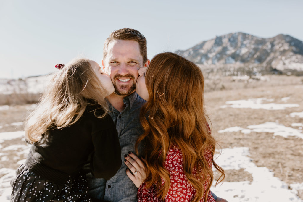 mom and daughter kissing dad's face for family photo